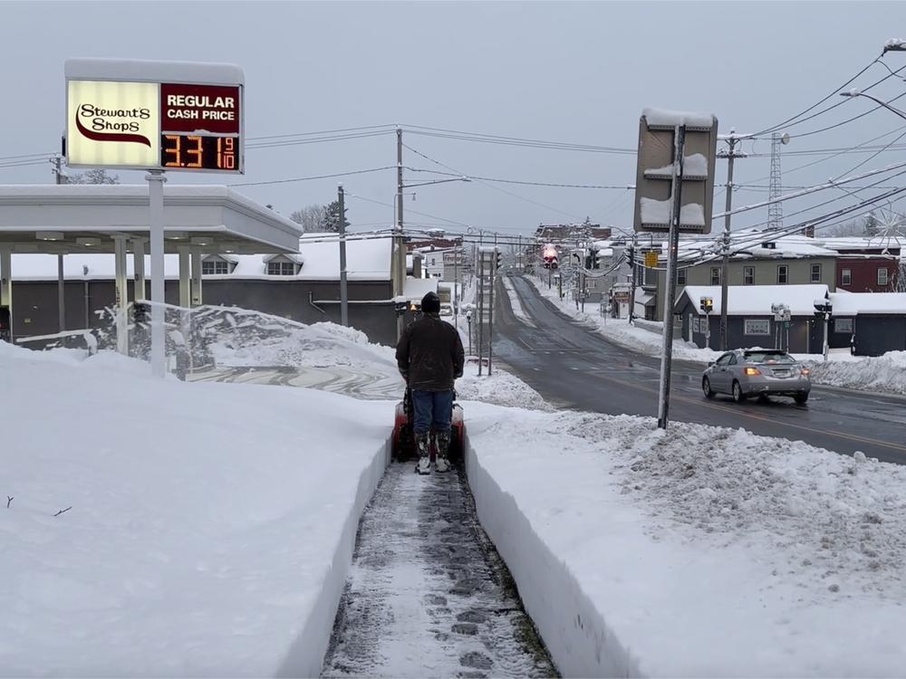 A person clears the snow from the sidewalk in Lowville, N.Y., on Saturday, Nov. 30, 2024.