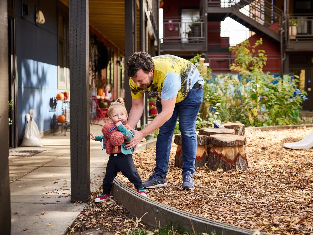 Pat Brennan-Arnopol and his daughter Alma, who is almost 2 years old, enjoy the shared playground in the courtyard at Daybreak Cohousing.