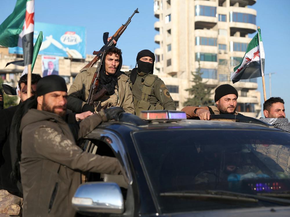 Antigovernment fighters brandish their guns as they ride a vehicle in Syria's northern city of Aleppo on Nov. 30.