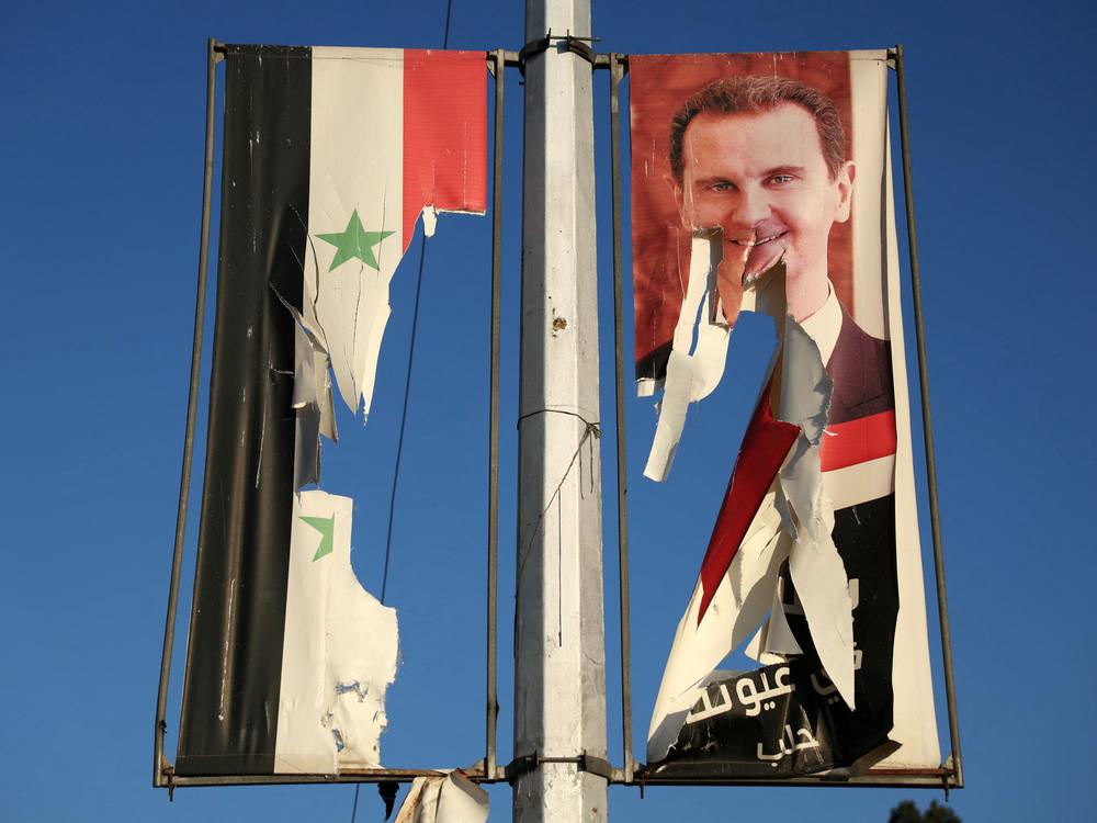 A billboard bearing a picture of Syria's President Bashar al-Assad and a national flag are torn by antigovernment fighters in the northern city of Aleppo on Nov. 30.