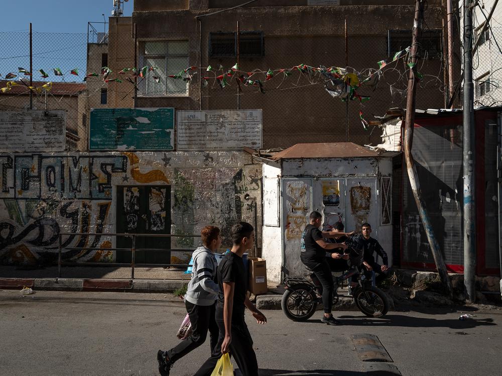 People walk past an UNRWA building in Am'ari, east of the city of Ramallah, in the West Bank on Nov. 13.