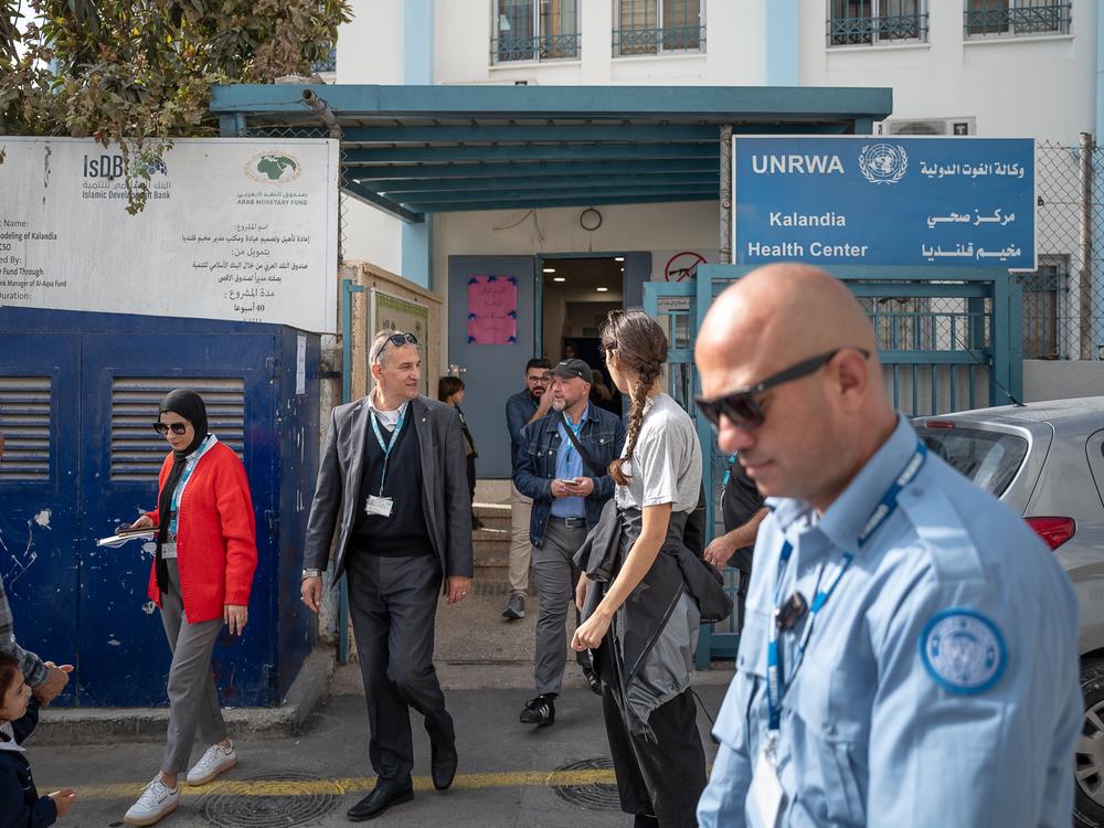 People walk by a health clinic administered by UNRWA in Qalandia refugee camp.