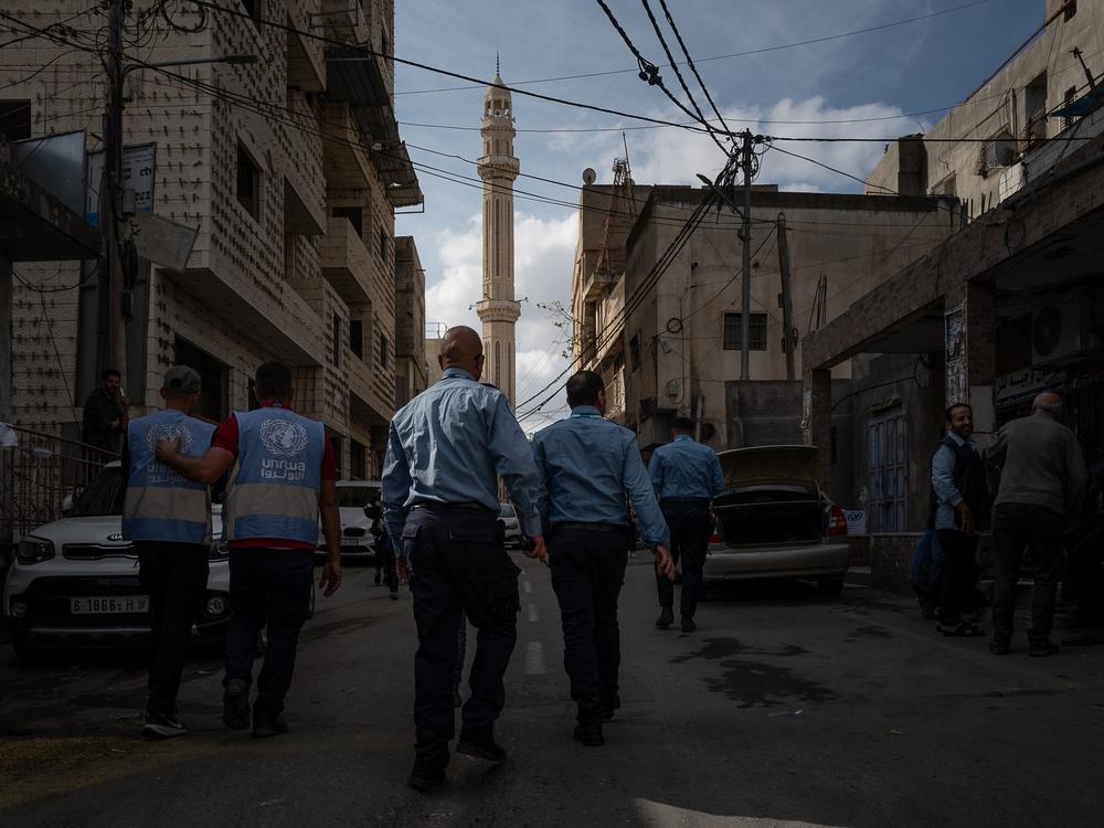 UNRWA staff and security walk along the street in Qalandia on Nov. 14.