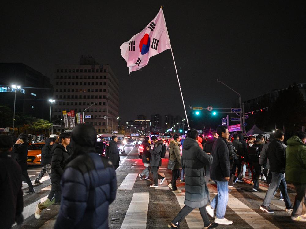 A man holds the South Korean flag outside the National Assembly in Seoul early Wednesday, after President Yoon Suk Yeol declared emergency martial law.
