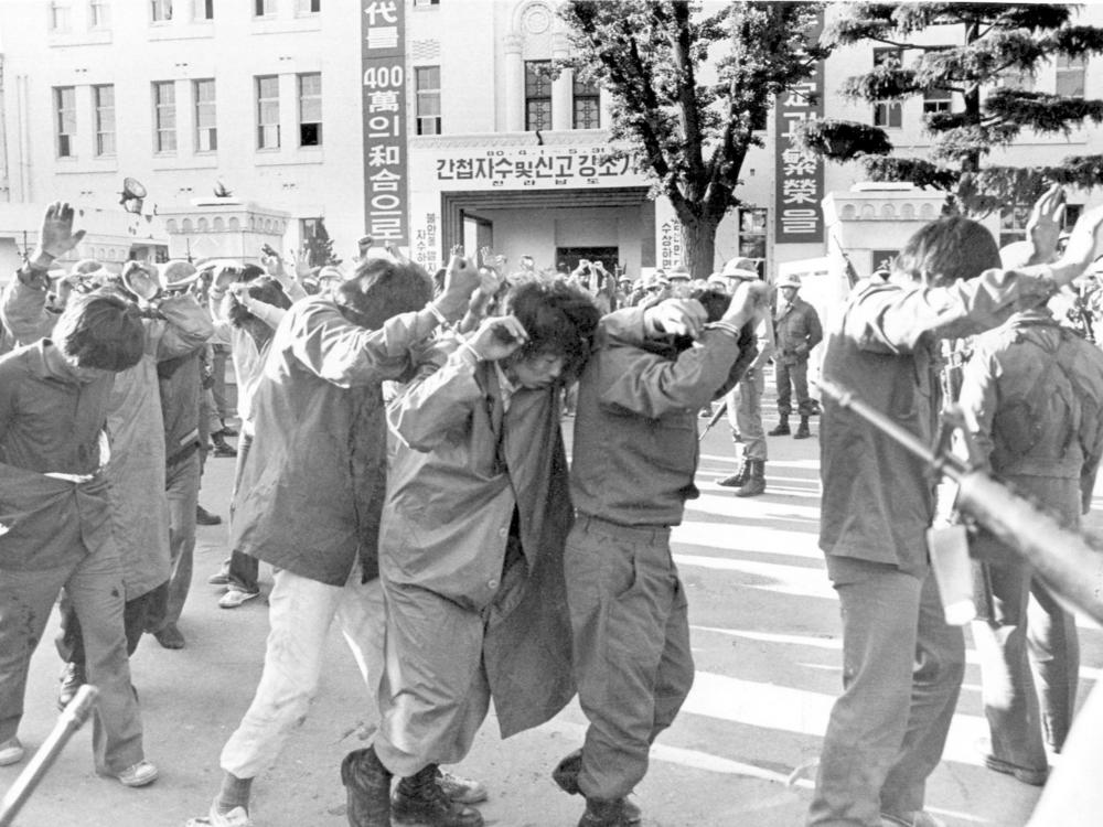 Captured protesters with hands up are led away by government forces on May 27, 1980, in Gwangju, South Korea.