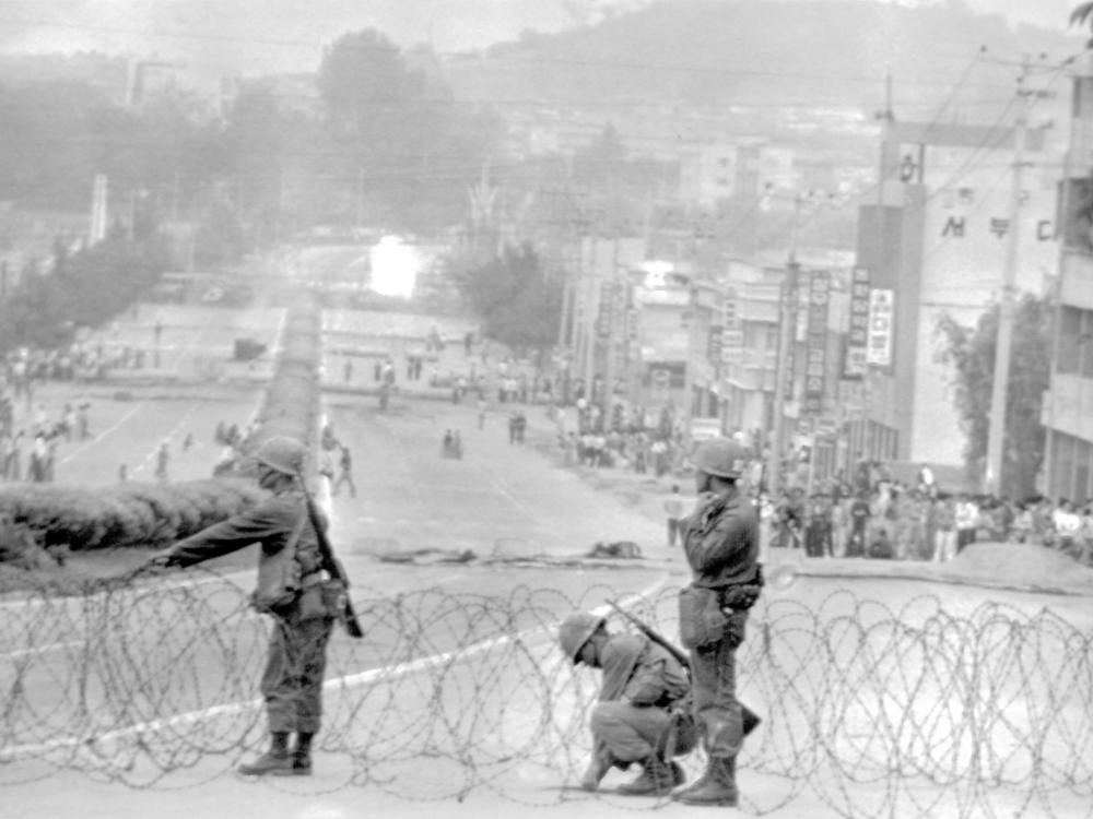 Government soldiers erect a roadblock on a street leading to downtown Gwangju, South Korea, with citizens looking on, on May 26, 1980.