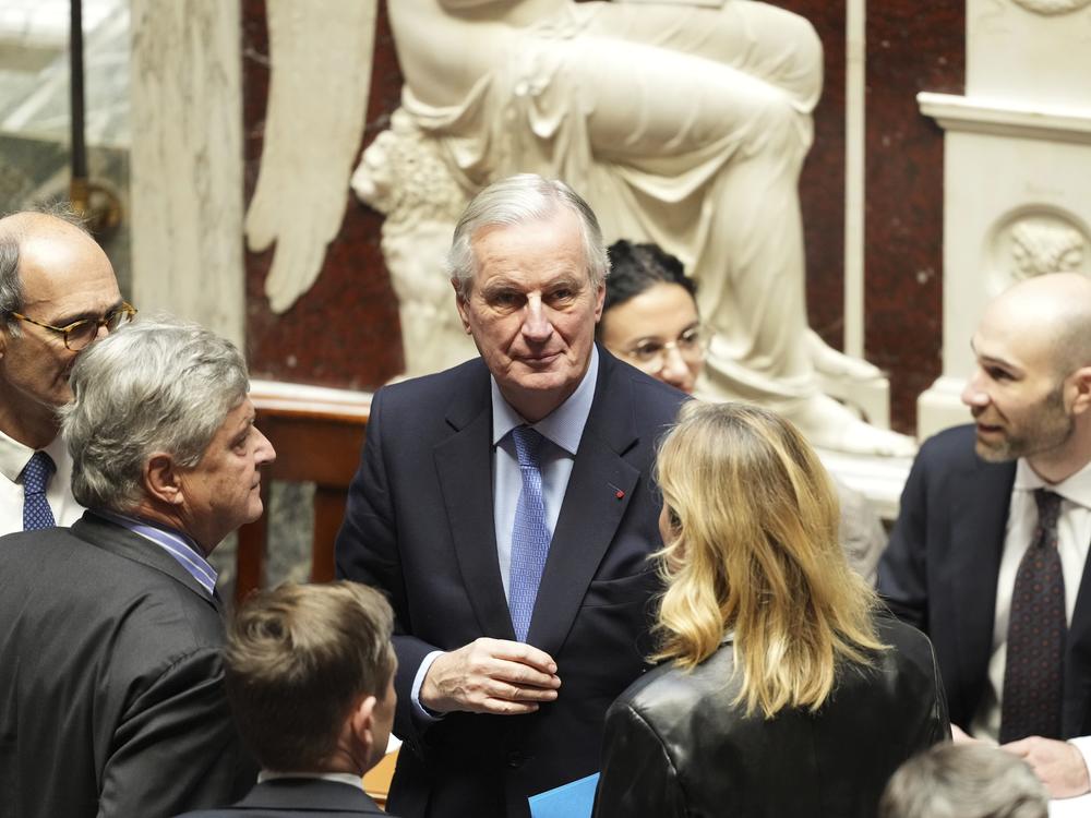 French Prime Minister Michel Barnier (center) talks to people at the National Assembly before French lawmakers vote on a no-confidence motion in Paris Wednesday.
