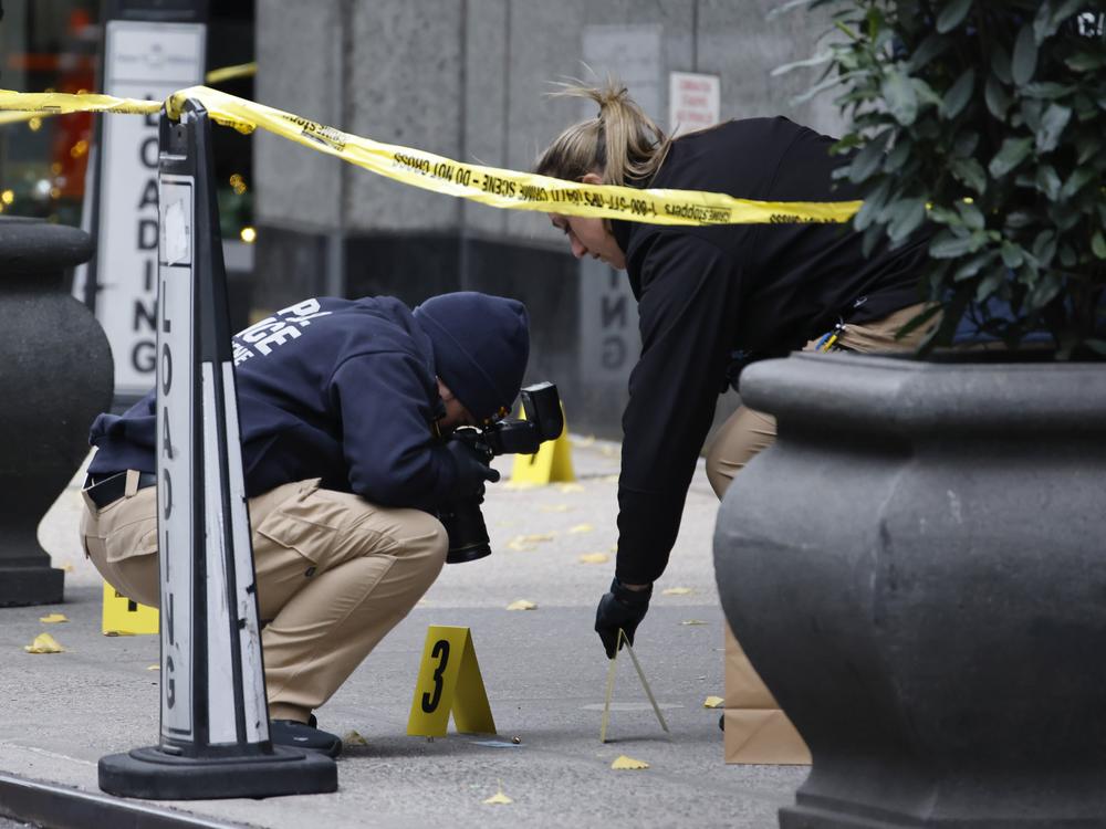 Members of the New York police crime scene unit photograph bullets lying on the sidewalk as they investigate the scene outside the Hilton Hotel in midtown Manhattan where Brian Thompson was fatally shot on Wednesday.