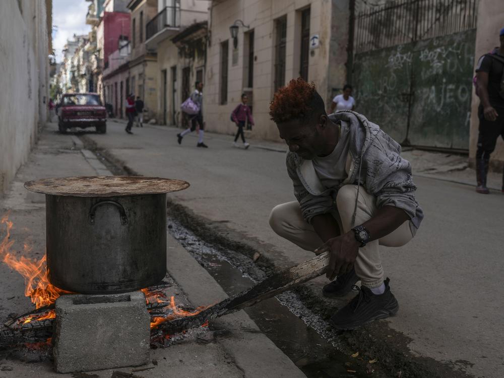 A man cooks soup over an open fire on a sidewalk, during a blackout in Havana, Cuba, on Wednesday.