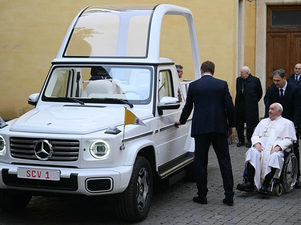 Pope Francis (right) looks on as he's presented a new fully electric popemobile at the Vatican on Wednesday.