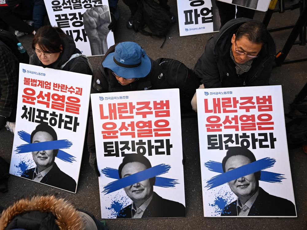 Members of the Korean Confederation of Trade Unions hold placards reading 