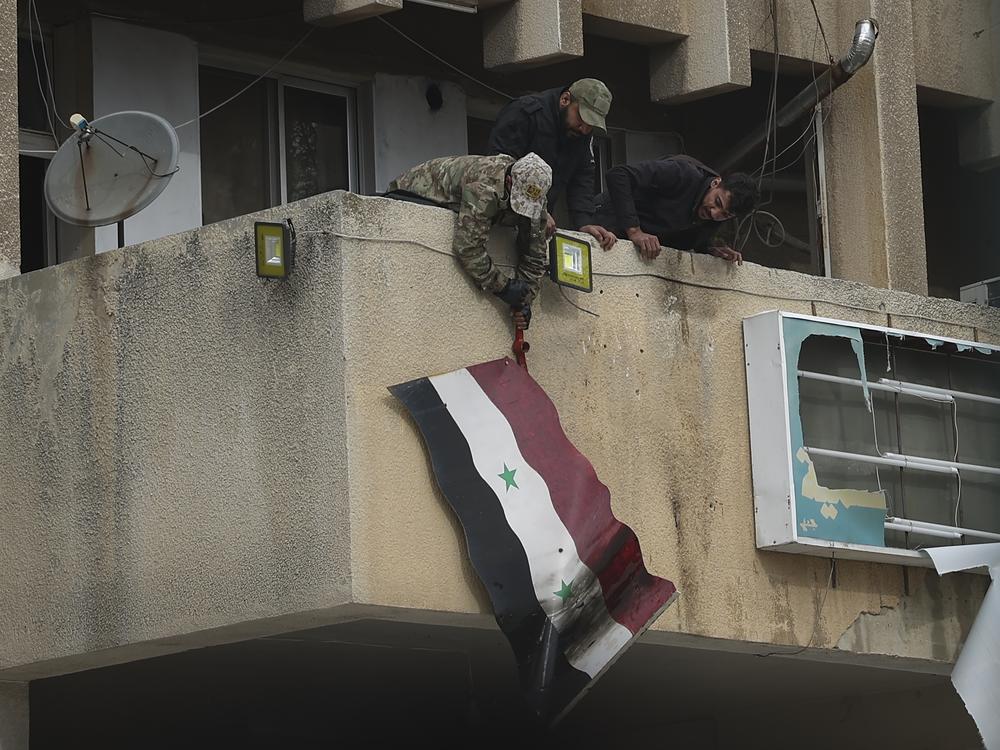 Syrian opposition fighters remove a government Syrian flag from an official building in Salamiyah, east of Hama, Syria, on Saturday.