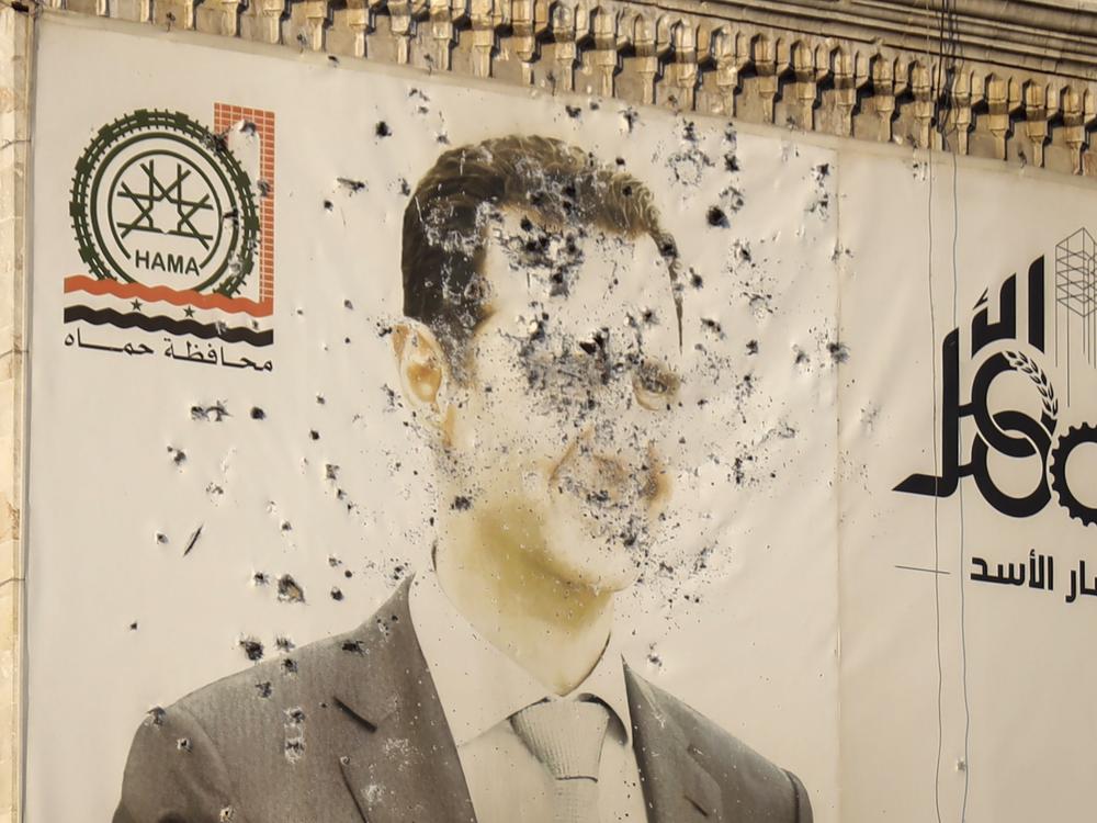 An image of Syrian President Bashar Assad, riddled with bullets, is seen on the facade of the provincial government office in the aftermath of the opposition's takeover of Hama, Syria, Friday, Dec. 6, 2024.