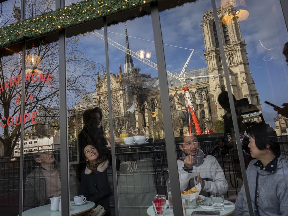 Customers sit inside a restaurant next to France's iconic Notre Dame Cathedral, hours before formally reopening its doors on Saturday.