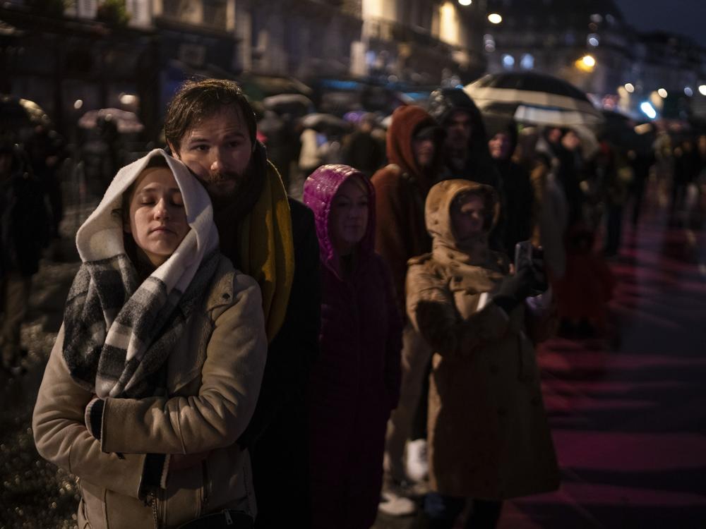 Spectators gather outside France's iconic Notre Dame Cathedral on Saturday in Paris for its formal reopening.