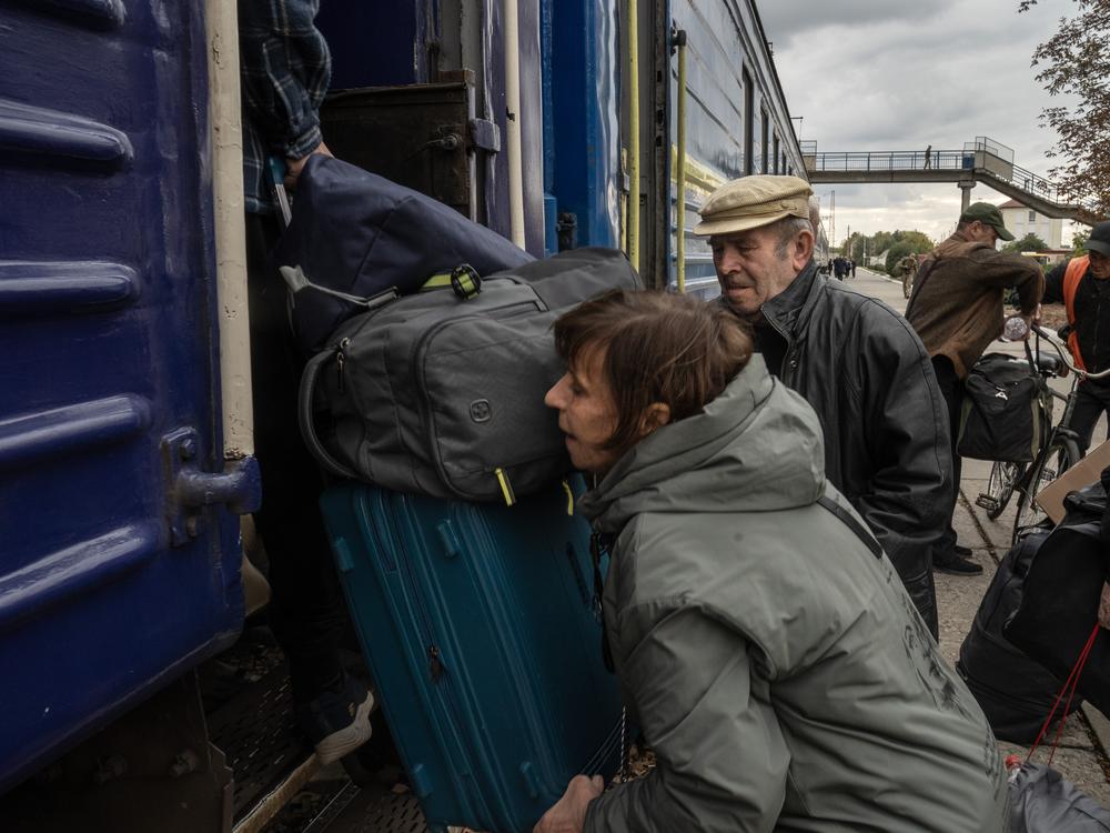 A displaced woman from eastern Ukraine's Donbas region lifts her luggage onto a train that leaves daily for Dnipro from the station in the mining city of Pavlohrad. From Dnipro displaced people are fanning out into western Ukraine and into Europe to stay with relatives.