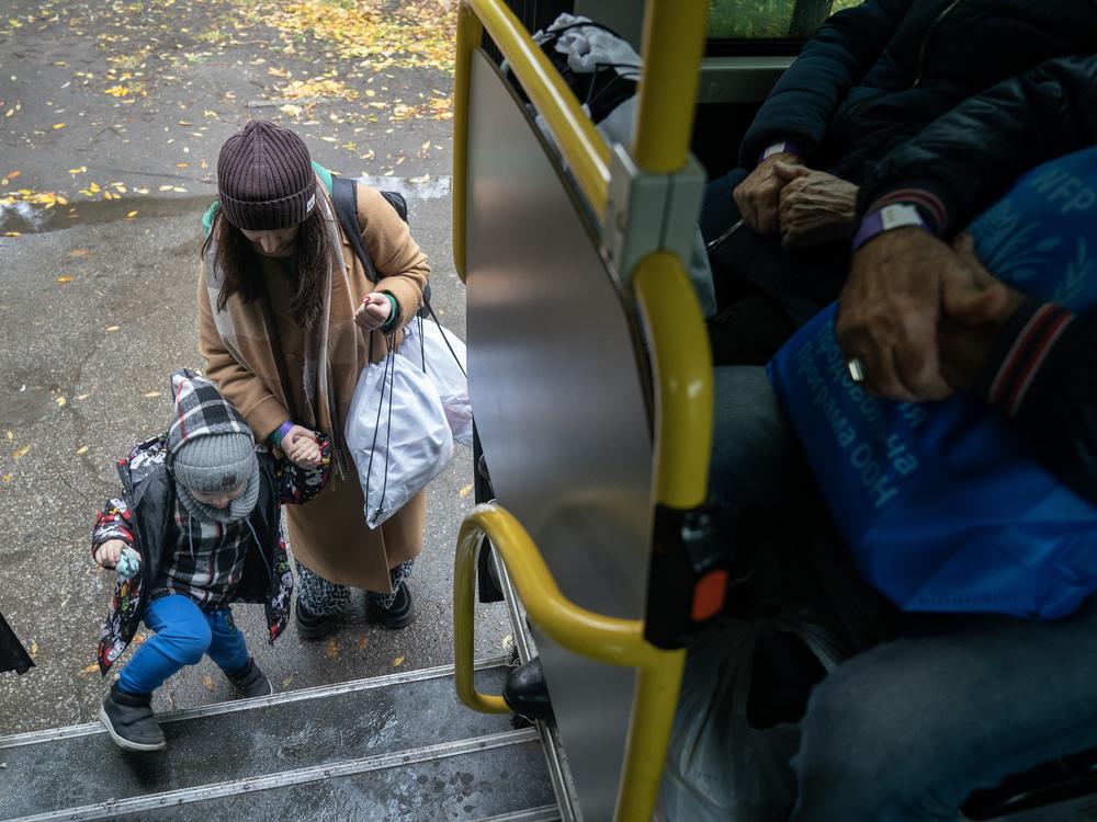 A mother and her child from the city of Pokrovsk, Ukraine, board a bus joining other evacuees in Pavlohrad, on Oct. 19. They were transferred to a train headed for western Ukraine or farther into Europe. Pokrovsk, a coal mining center in eastern Ukraine, is under frequent artillery barrages and aerial attacks by the Russians who are making a push into the region.