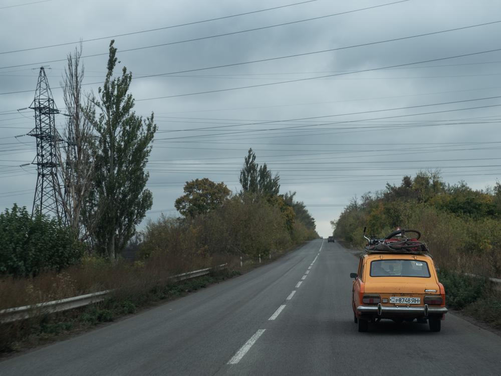 A car loaded with suitcases and a bicycle heads west on the main highway from Dobropillya, Ukraine, in October. The number of displaced people fleeing the Pokrovsk region has grown as Russian troops continue a steady advance on the coal producing area.