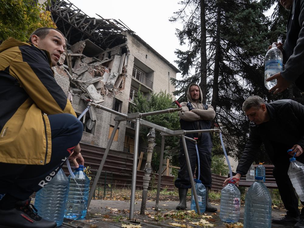 Residents fill bottles with water from a public spigot in front of a bombed-out student dormitory in the coal mining town of Dobropillya, Ukraine, on Oct. 17.