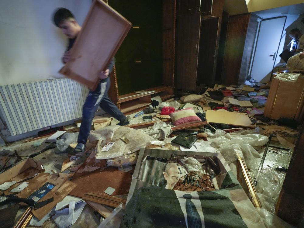 A man walks by a broken portrait of the late Syrian President Hafez Assad as people search for belongings in the ransacked private residence of Syrian President Bashar Assad in the Malkeh district of Damascus, Syria, on Sunday.