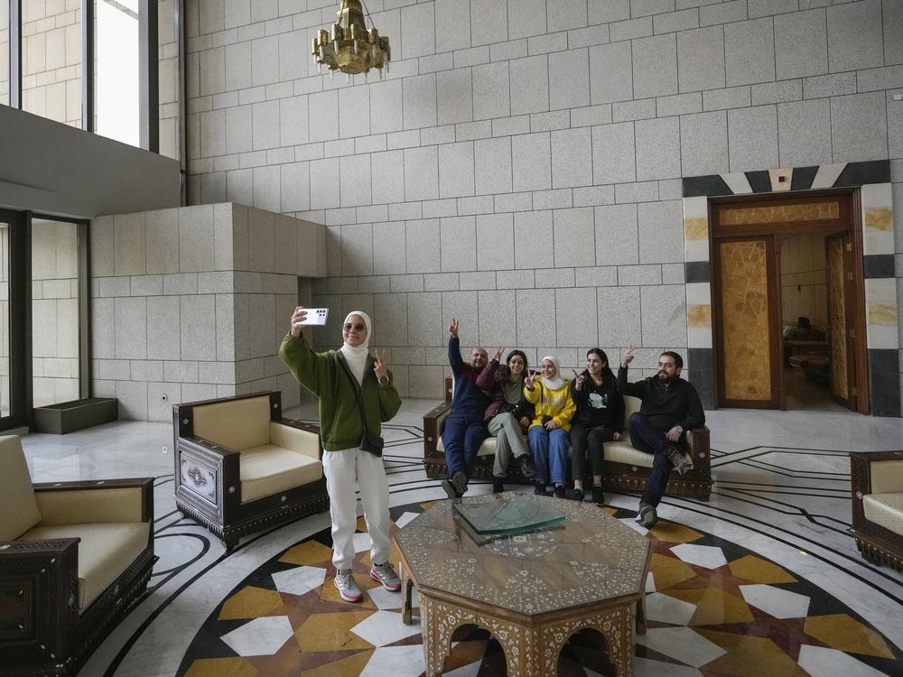 A group of people take a family photo while sitting on a couch in a hall of Syrian President Bashar Assad's presidential palace in Damascus, Syria, Sunday.