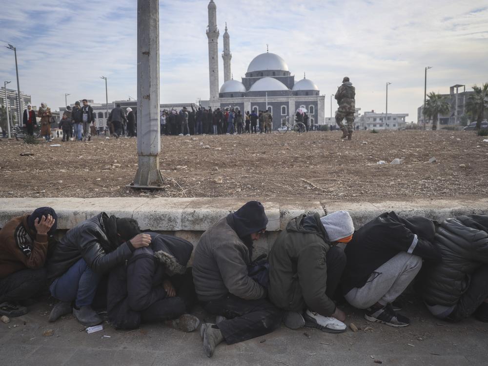 Government soldiers and their allies huddle on the ground while being detained by insurgents in Homs, Syria.
