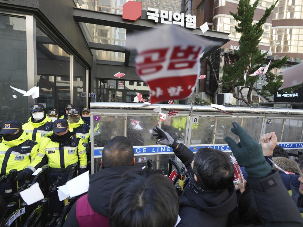 Members of the Korean Confederation of Trade Unions throw torn papers carrying the names of the ruling party's lawmakers who didn't vote at the impeachment motion last week, during a rally in front of the ruling People Power Party's head office in Seoul, South Korea on Monday.