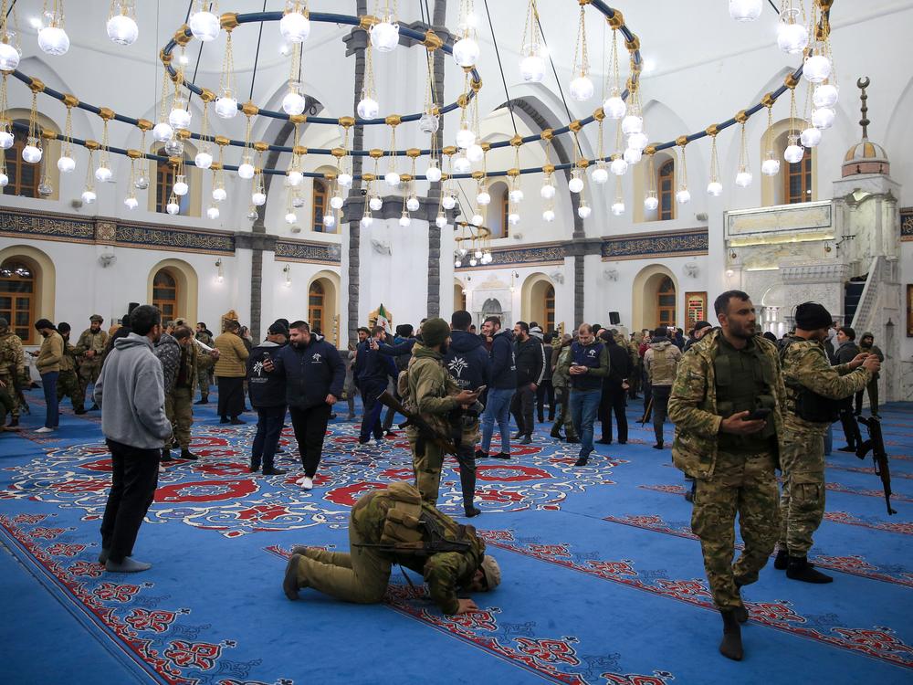 Syrian Islamist-led rebel fighters pray in a mosque in the central city of Homs early on December 8, 2024, after entering Syria's third city overnight.