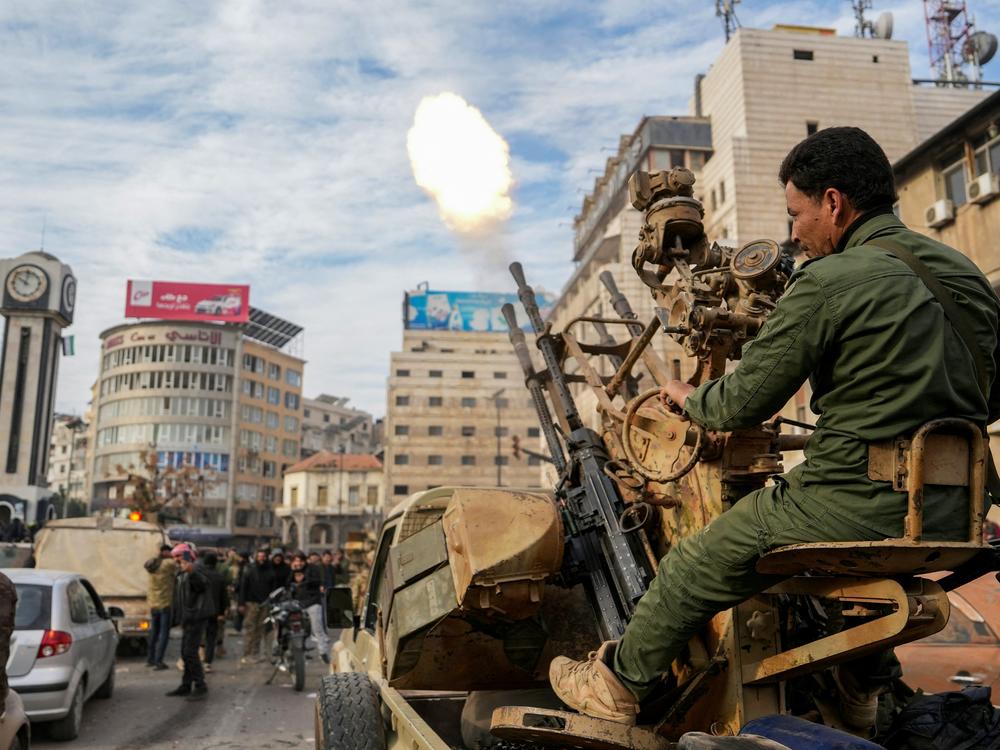 A Syrian rebel fighter fires rounds as people celebrate near the Clock Tower in the central city of Homs, after rebel forces entered Syria's third city overnight.