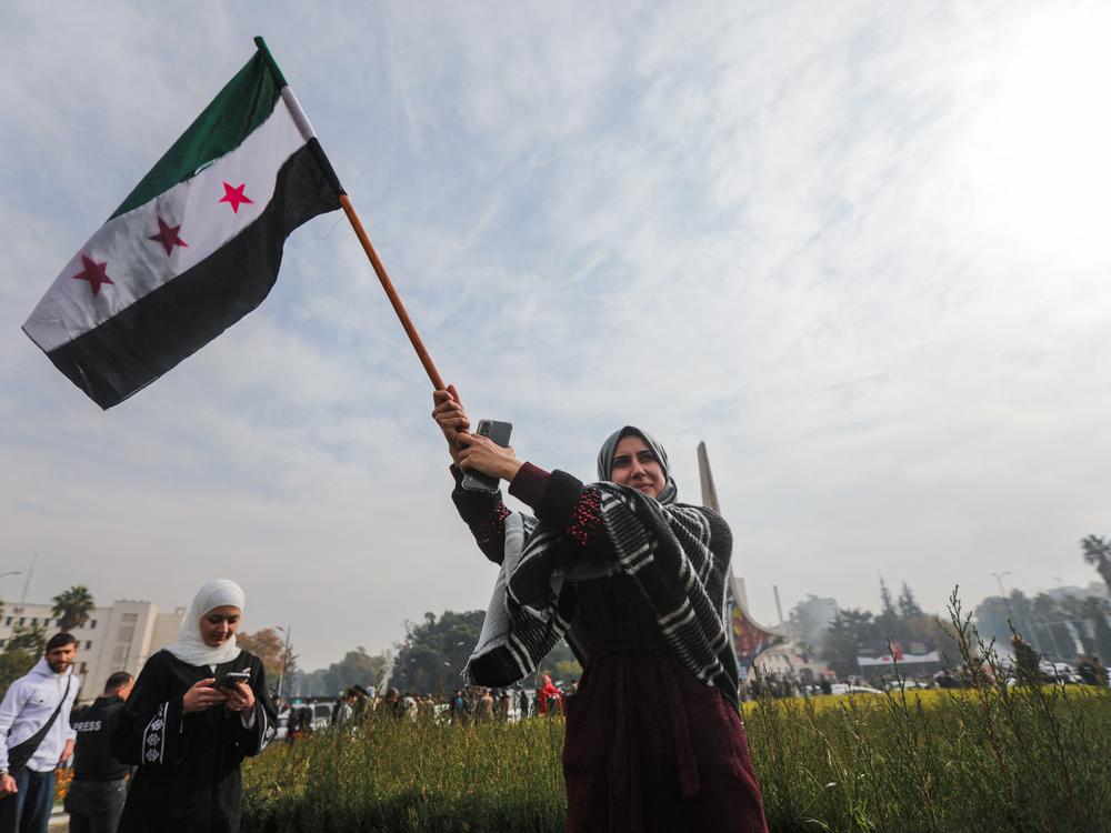 A woman waves a Syrian opposition flag as she celebrates at Umayyad Square in Damascus.