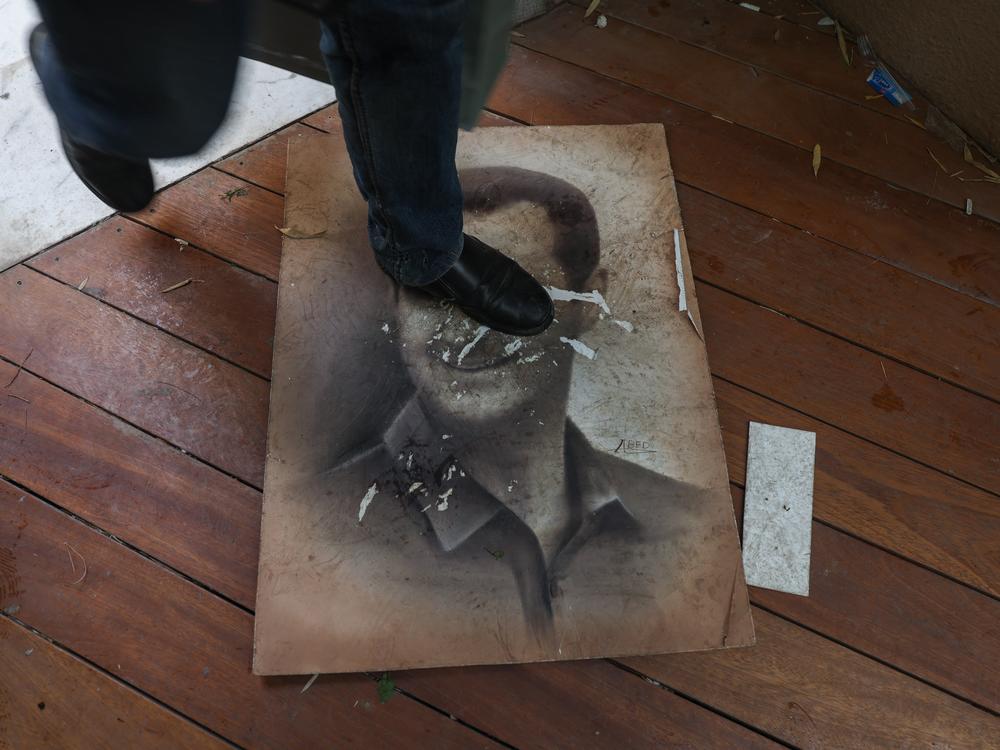 A man steps on a picture of Syria's ousted president Bashar al-Assad as people enter his residence in Damascus' Malki area after Islamist-led rebels declared that they have taken the Syrian capital in a lightning offensive, sending al-Assad fleeing and ending five decades of Baath rule in Syria.