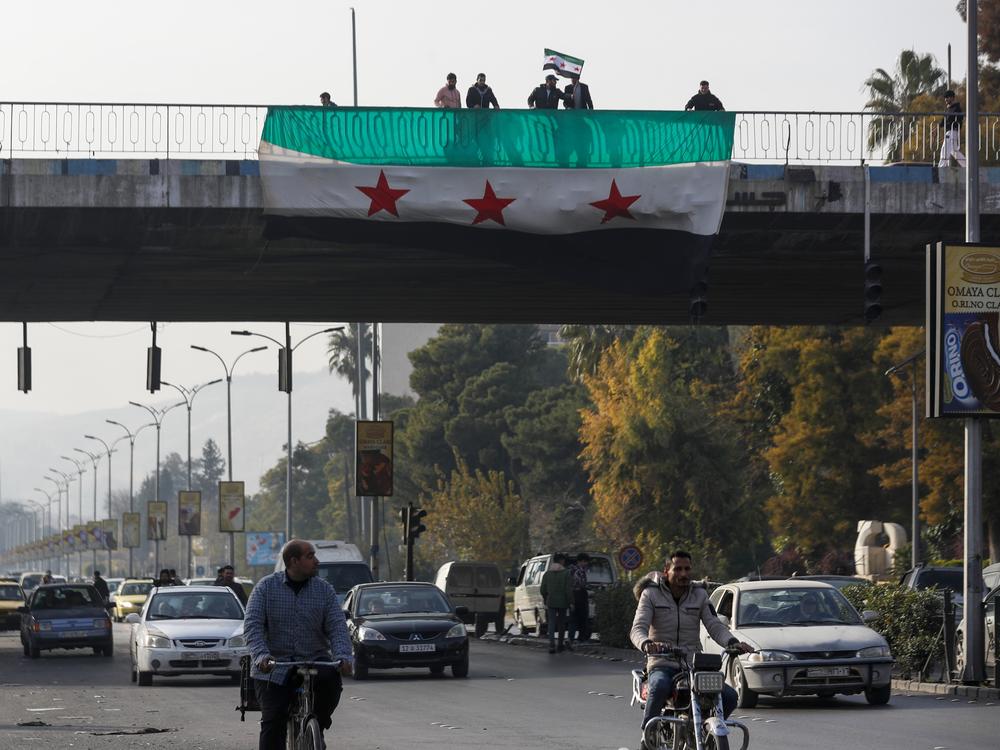 Syrians wave the Syrian opposition flag as they celebrate the ouster of former leader Bashar al-Assad in Damascus. Assad and his father, Hafez al-Assad, combined to rule Syria for more than 50 years.