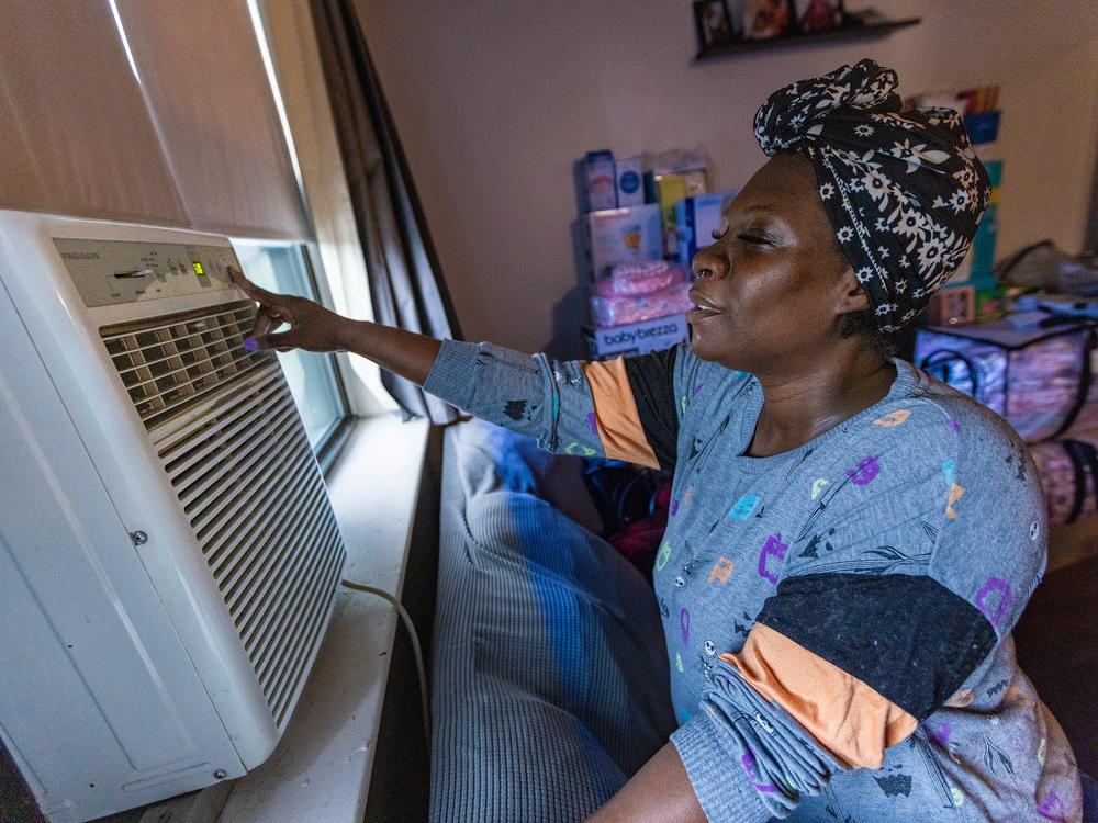 Kiki Polk, one of the first Boston Medical Center patients to enroll in the Clean Power Prescription program, turns on the air conditioner in her home in Boston.