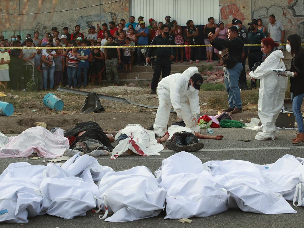 Bodies in bodybags are placed on the side of the road after a deadly semi-trailer truck crash in Tuxtla Gutierrez, Chiapas state, Mexico, Dec. 9, 2021.