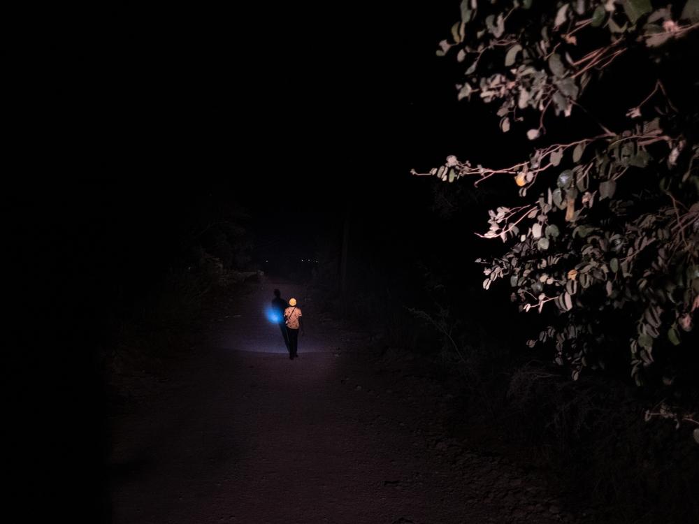 A man uses the light from his mobile phone to navigate an otherwise pitch dark road in an area frequented by elephants in Livingstone, Zambia, where incidents of human-wildlife conflict have been on the rise.