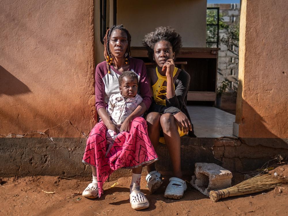 Janet Sikabonga, 36, and her daughter, Hilda Masombo, 17, of Livingstone, Zambia, sit on their front porch the morning after elephants raided their yard, destroying their water tap and laundry line. They say that elephants had previously destroyed their vegetable patch and fruit trees.