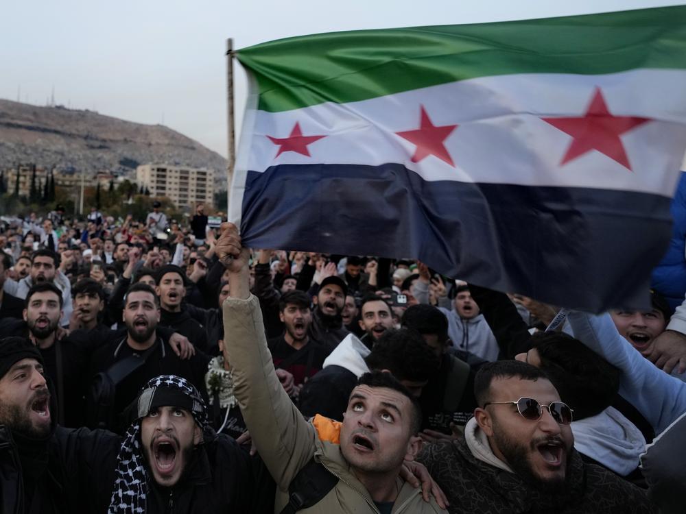 Syrian citizens wave the revolutionary flag and shout slogans, as they celebrate during the second day of the take over of the city by the insurgents in Damascus on Monday.
