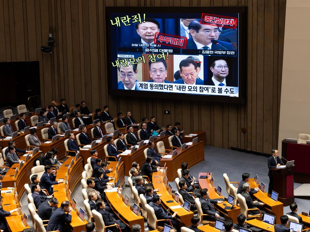 A screen displays photographs of South Korean President Yoon Suk Yeol (top left) and former and current cabinet ministers, accusing them of treason, during a plenary session at the National Assembly in Seoul, South Korea, on Wednesday. Yoon looks set to fight on rather than step down early as probes deepen into his martial law declaration and another likely impeachment bid loom.