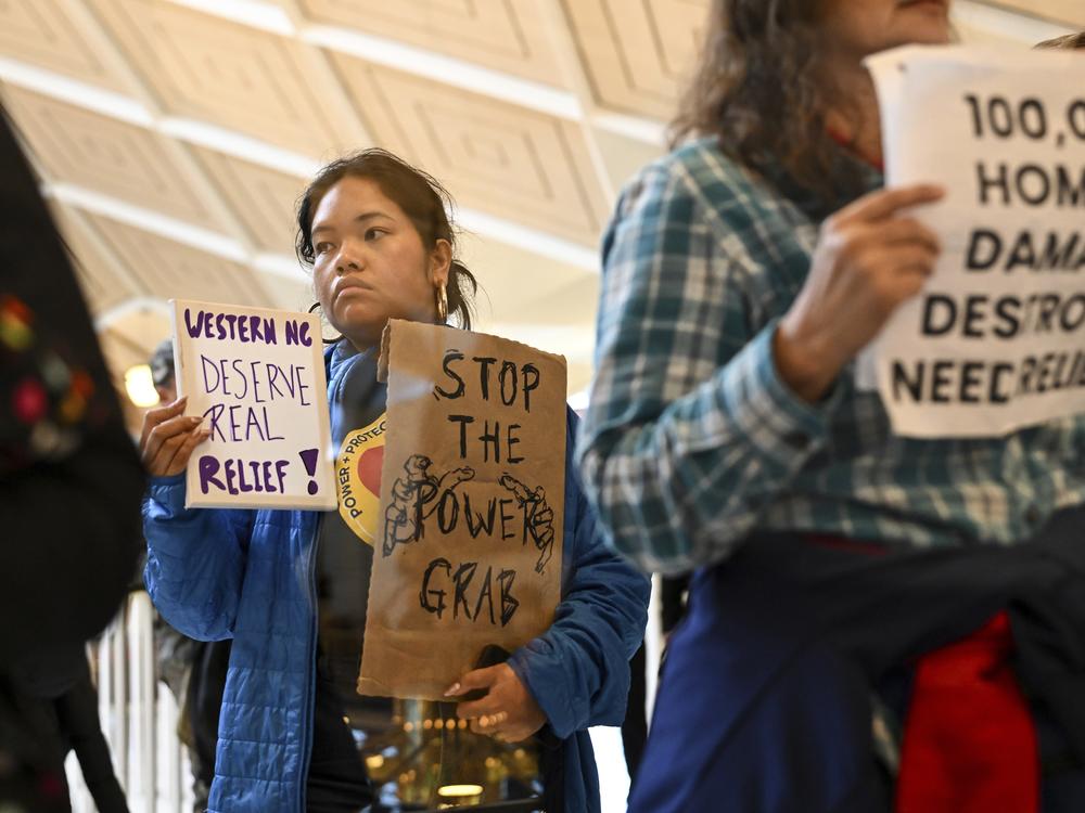 A protester holds a sign as the Republican-dominated North Carolina House convened to complete the override of Gov. Cooper's veto, Dec. 11, 2024, in Raleigh, N.C.