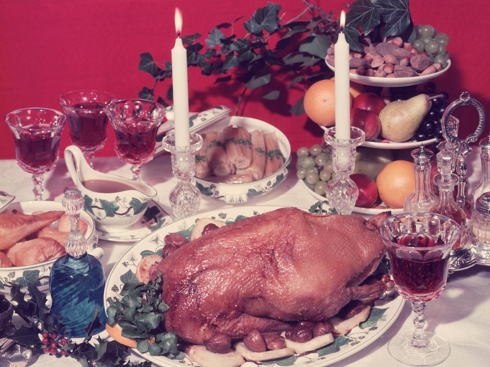 A traditional festive dinner table from 1955 decorated with sprigs of berried holly.