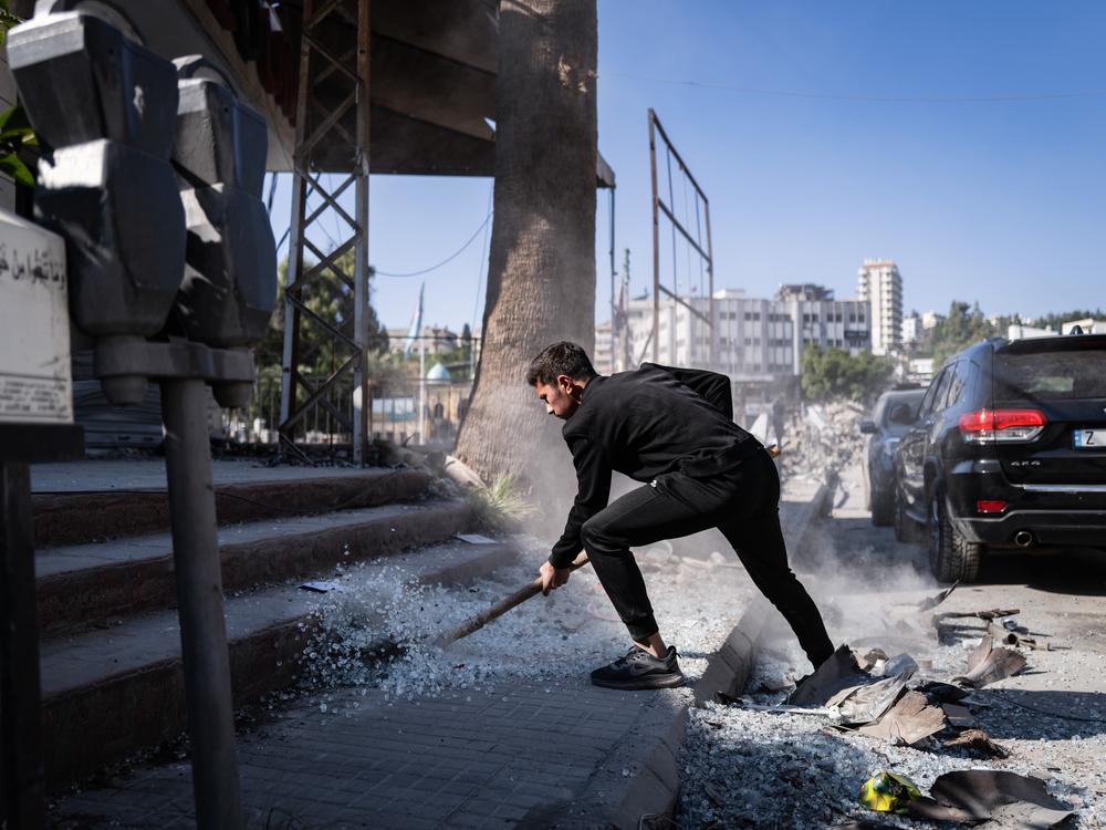 A resident of Nabatieh clears rubble and broken glass from the center of the city.