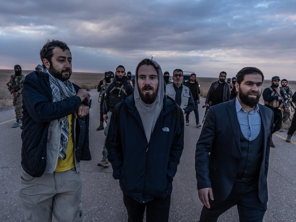 Timmerman (center) walks with Mouaz Moustafa (left) and an interim Syrian government official before his handover to U.S. forces in southern Syria on Friday.