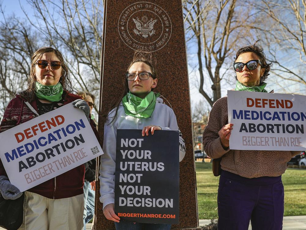 Three members of the Women's March group protest in support of access to abortion medication outside the Federal Courthouse on March 15, 2023, in Amarillo, Texas.