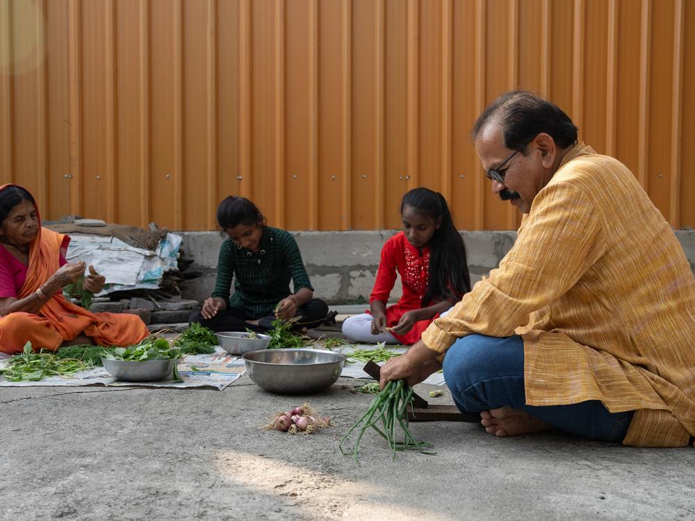 Shahu Patole sorts and cuts greens with family members.