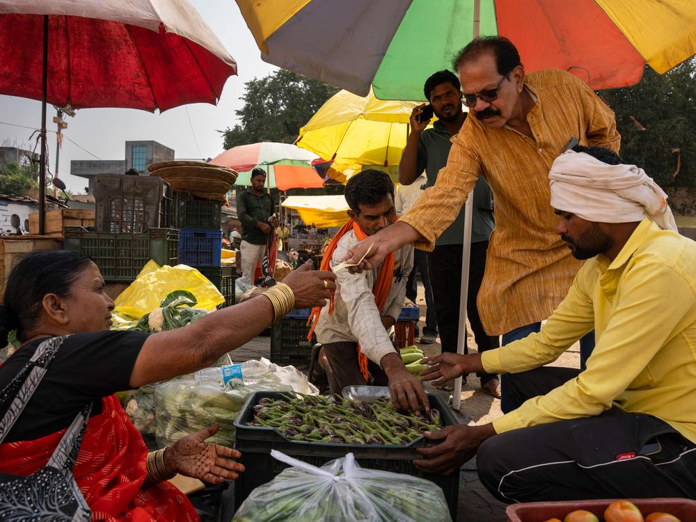 Cookbook author Shahu Patole buys vegetables in an open air market.