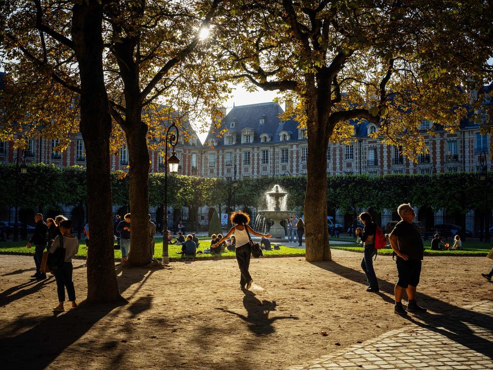 People stroll at Place des Vosges during a sunny afternoon in Paris on Oct. 3, 2023.