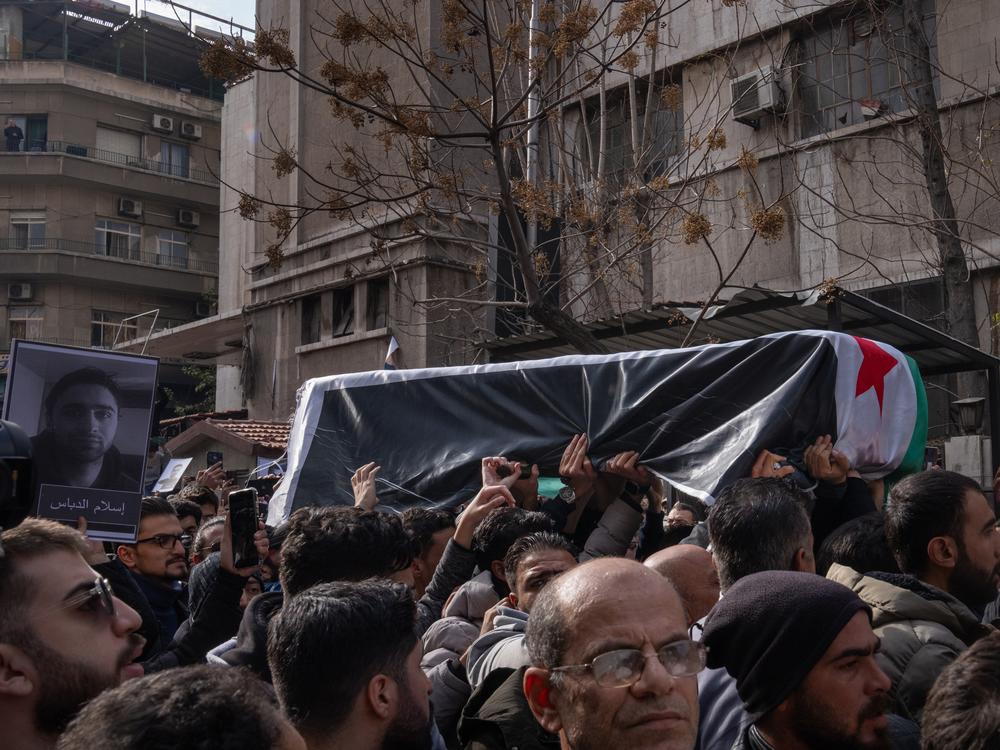 Mourners hold up the coffin of Syrian activist Mazen al-Hamada during a funeral procession through Damascus. Al-Hamada was severely tortured during the Assad regime.