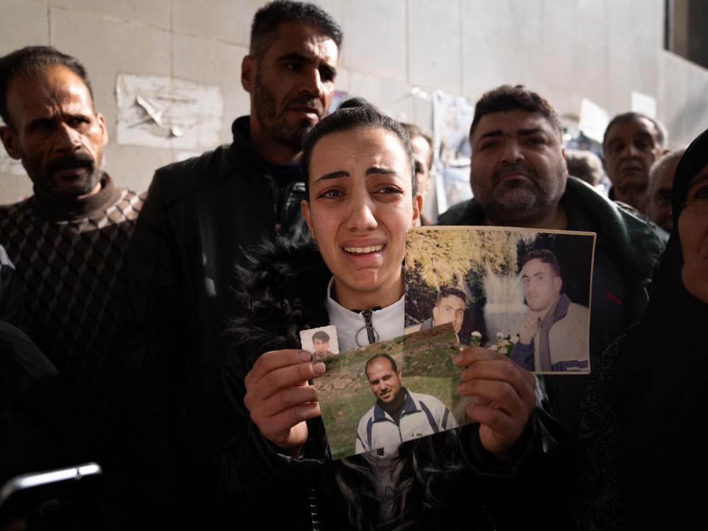 Sarah Abdel Hamid Al-A'ami holds photos of her 4 brothers who were all accused of terrorism under the Assad regime, and though she came to search posters of dead bodies, she still hasn't found any signs of them.