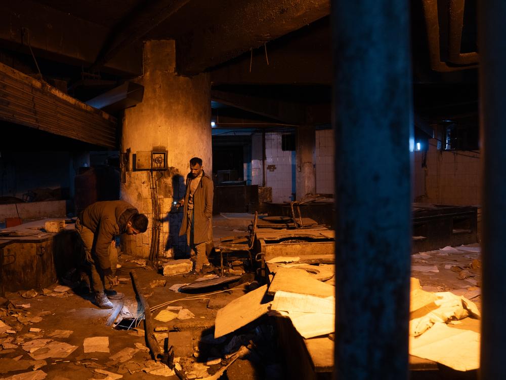 People look in holes in the floor of a room in Sednaya prison. Documents are strewn across the floor. Many families are coming to the prison to look for lost loved ones.