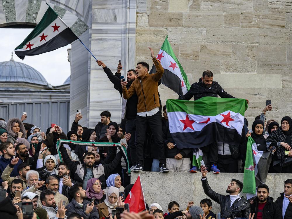 Syrian residents in Turkey wave Syrian opposition flags as they celebrate the President Bashar al-Assad's rule in Syria after rebel fighters took control of Damascus overnight, at the Fatih Mosque, in Istanbul, on Sunday.
